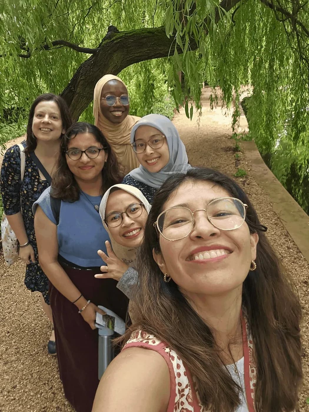A group taking a selfie together beneath a willow tree